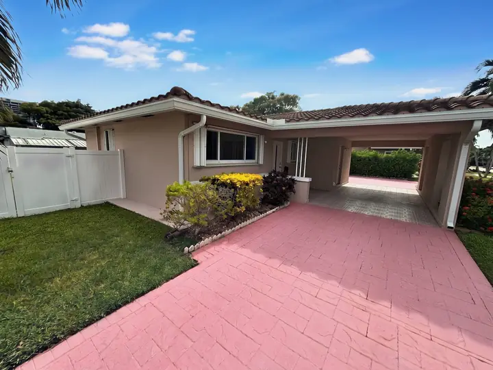 Fachada da casa de temporada em Hallandale Beach com entrada de pavers cor-de-rosa e garagem coberta