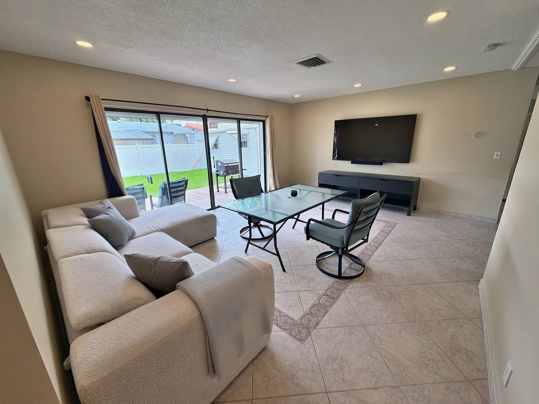 Living room of the Hallandale Beach vacation rental with sectional sofa, TV and sliding doors to the backyard
