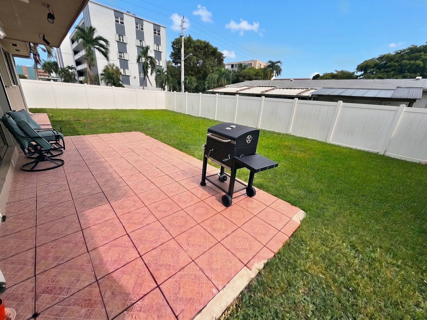 Private fenced backyard with paved patio, lawn and BBQ at the Hallandale Beach rental house